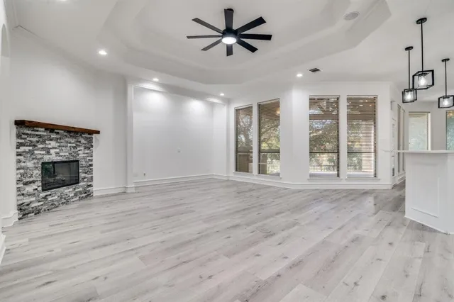 an empty room with wooden floor a ceiling fan and windows