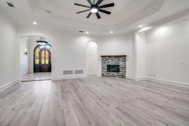 an empty room with wooden floor a ceiling fan and a fireplace