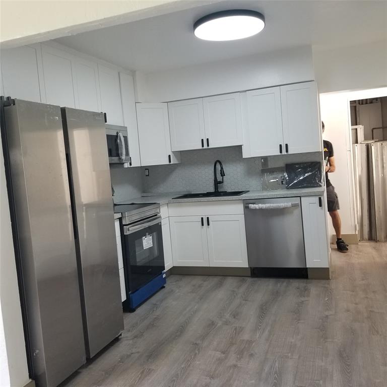 803 Northeast 8th Street Hallandale Beach, FL 33009 - Photo 22 of 38 a kitchen with stainless steel appliances granite countertop a refrigerator a sink a stove a microwave and island