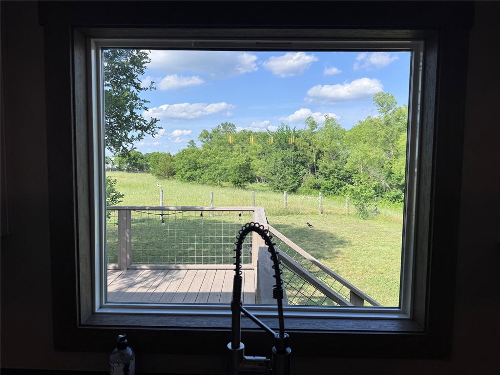 7268 Brangus Road Anna, TX 75409 - Photo 6 of 21 Window framing a composite deck with wire railing, overlooking a green landscape with scattered trees and a clear sky