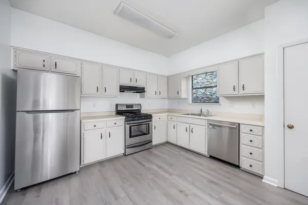 a kitchen with white cabinets white stainless steel appliances and wooden floors