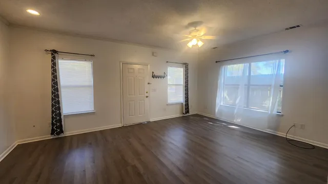an empty room with wooden floor and windows