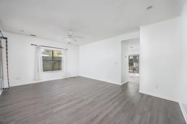 a view of an empty room with wooden floor and a window