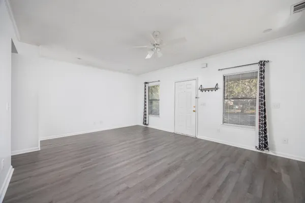 an empty room with wooden floor closet and windows