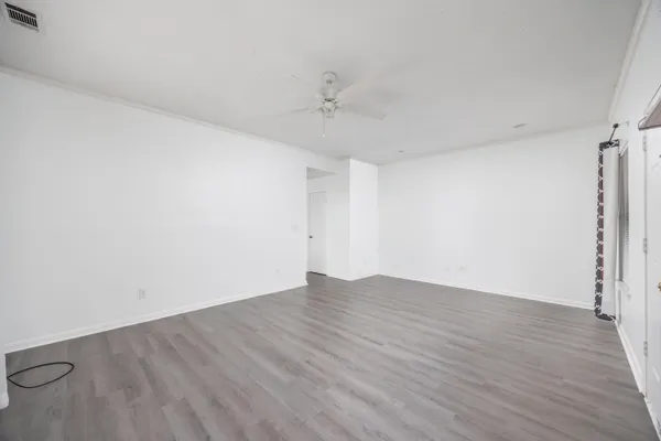 an empty room with wooden floor and ceiling fan