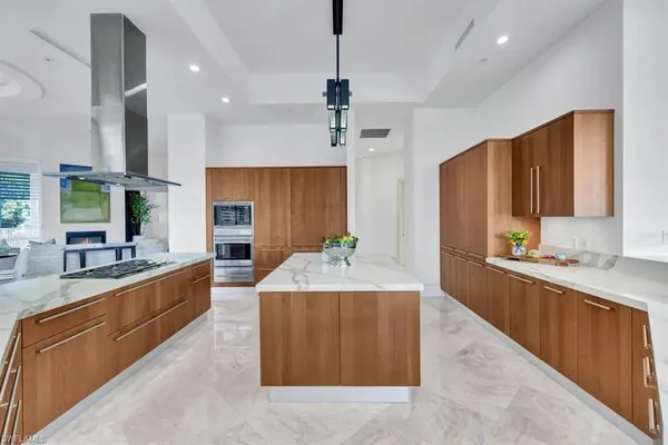 a large kitchen with stainless steel appliances a large counter top a sink a stove and a refrigerator