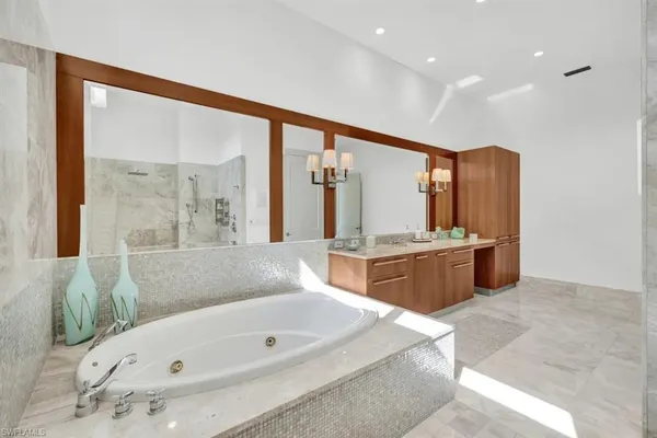 a bathroom with a tub a double vanity sink and mirror