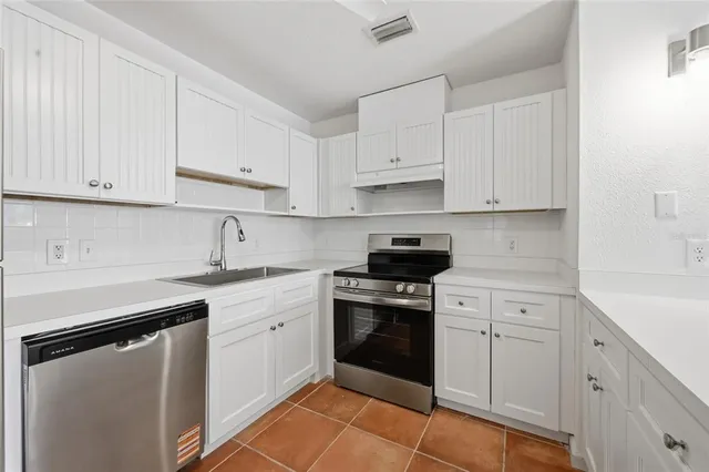a kitchen with cabinets appliances a sink and a counter top