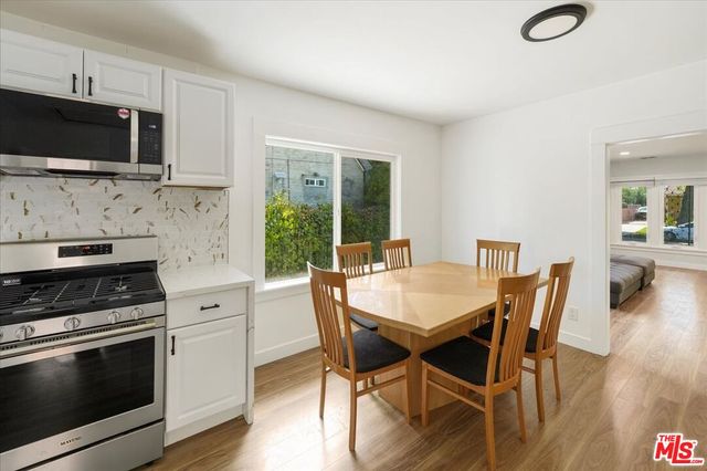 a kitchen with stainless steel appliances kitchen island granite countertop a stove top oven a sink a dining table and chairs