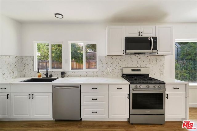 a kitchen with white cabinets stainless steel appliances and sink