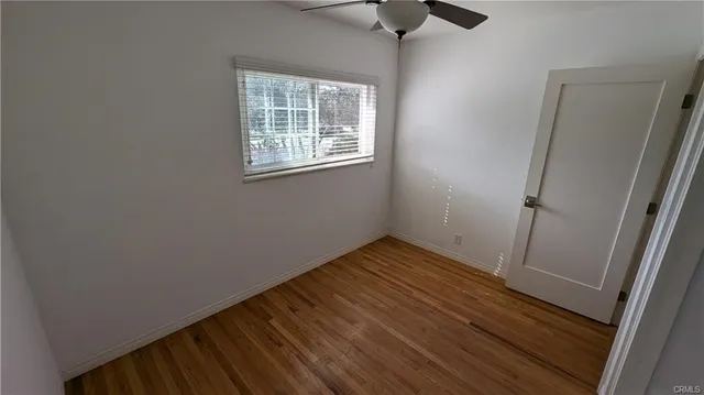 an empty room with wooden floor cabinet and windows