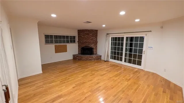 a view of an empty room with wooden floor and windows