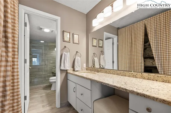 a bathroom with a granite countertop sink a mirror and shower