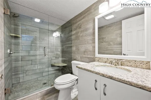 a bathroom with a granite countertop sink a toilet and shower