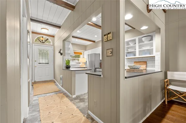 a view of a hallway with wooden floor and a kitchen