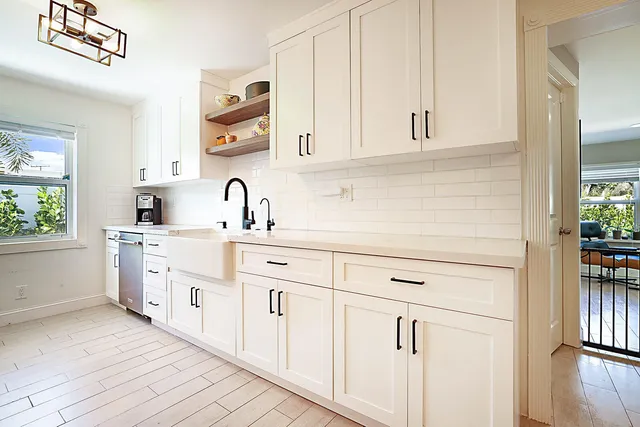 a kitchen with white cabinets and sink
