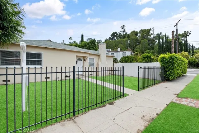 a view of a white house with a big yard and plants