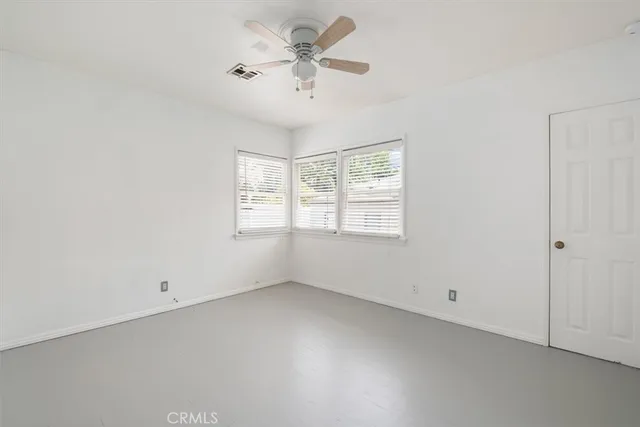an empty room with a window and a fan