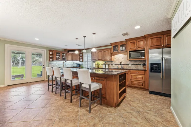 a kitchen with stainless steel appliances kitchen island granite countertop a table chairs and a refrigerator