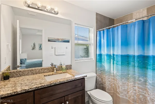 a bathroom with a granite countertop sink a toilet and shower