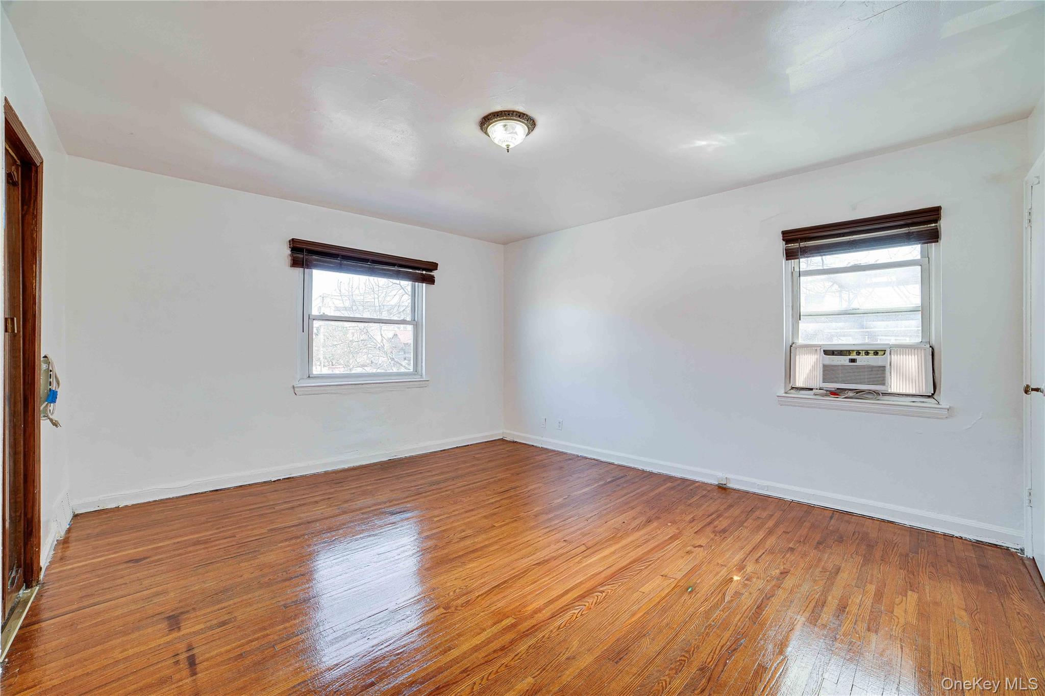 993 Duncan Street Bronx, NY 10469 - Photo 12 of 32 an empty room with wooden floor and windows