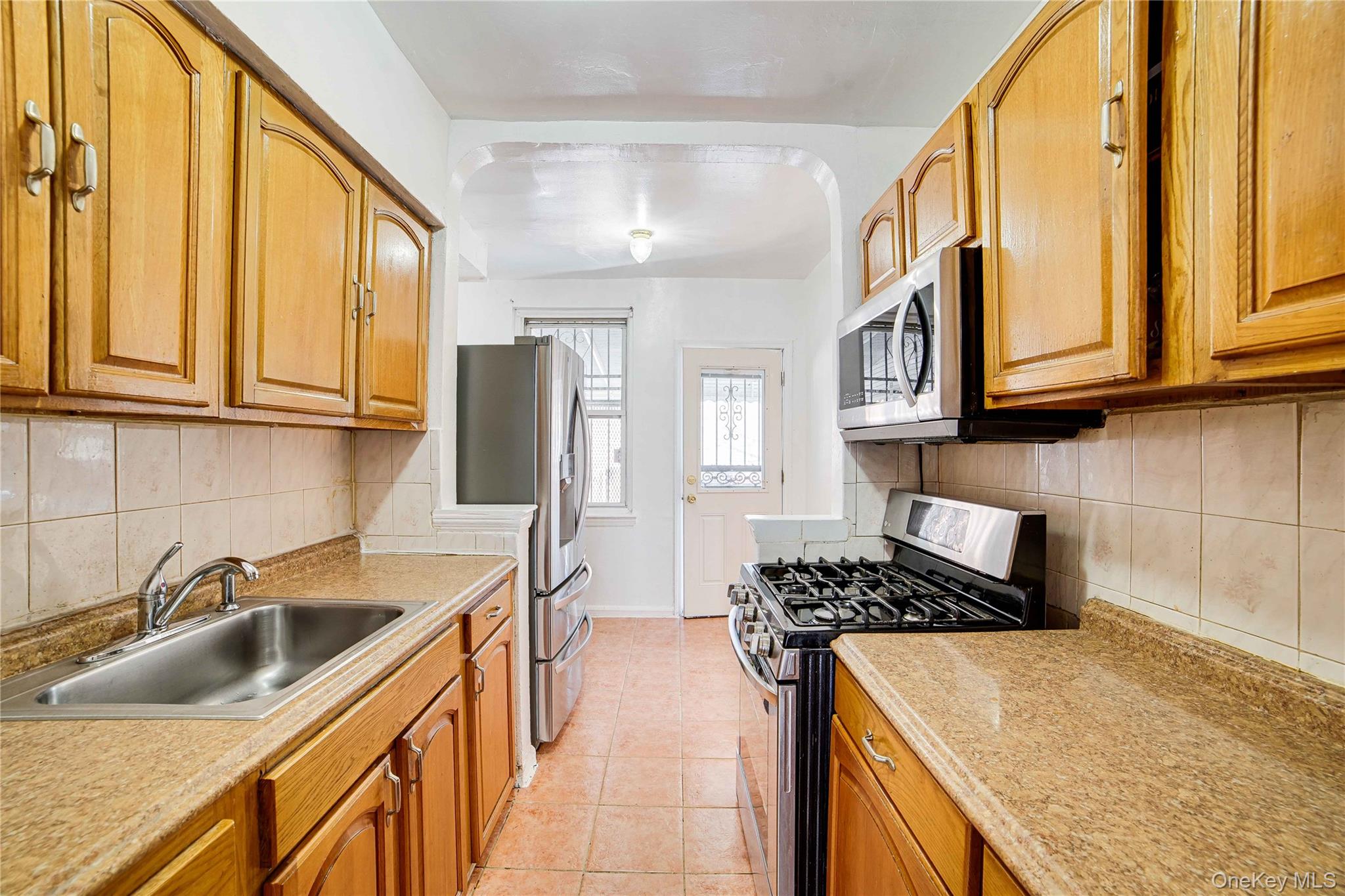 993 Duncan Street Bronx, NY 10469 - Photo 15 of 32 a kitchen with stainless steel appliances granite countertop a sink and cabinets