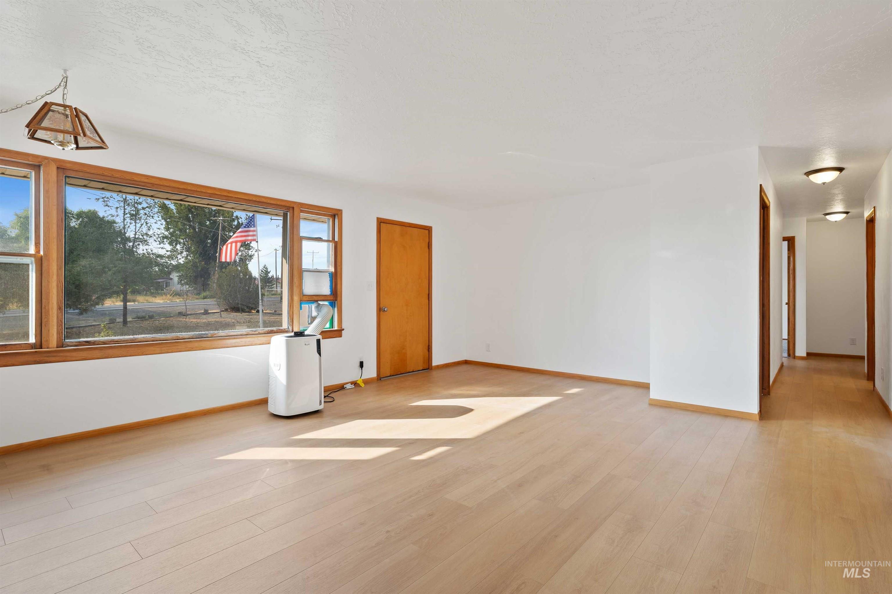 321 Clear Lakes Road Buhl, ID 83316 - Photo 5 of 34 Expansive interior with light wood-finish flooring, white walls, and a large window featuring wood trim