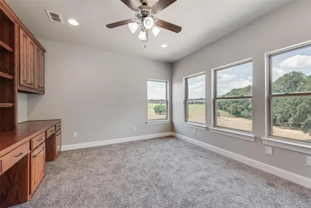 a big room with windows and chandelier fan