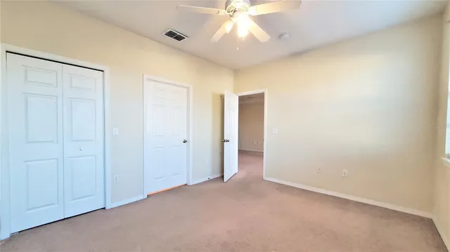 an empty room with a ceiling fan and a window