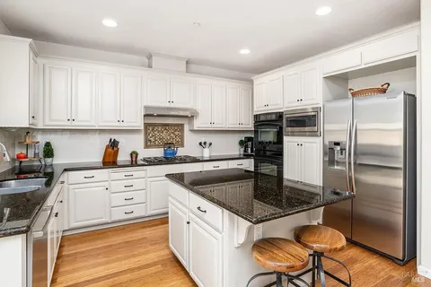 a kitchen with a refrigerator a stove a sink and white cabinets