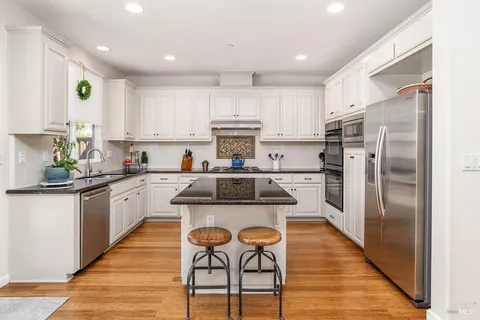 a kitchen with stainless steel appliances granite countertop a refrigerator sink and white cabinets