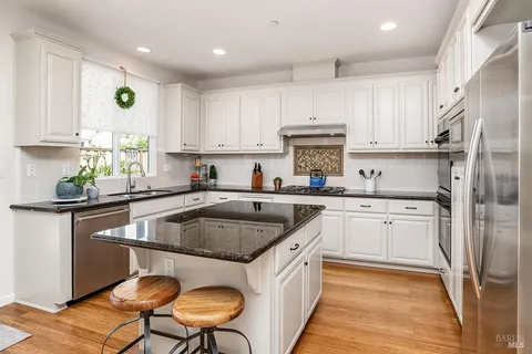 a kitchen with kitchen island granite countertop a sink cabinets and stainless steel appliances