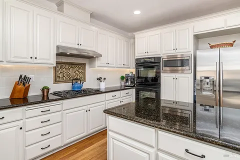 a kitchen with white cabinets and stainless steel appliances