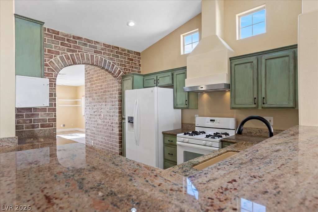 120 Ringlore Road Henderson, NV 89015 - Photo 14 of 58 Polished granite countertops surround this kitchen featuring a rustic brick archway and vaulted ceiling.
