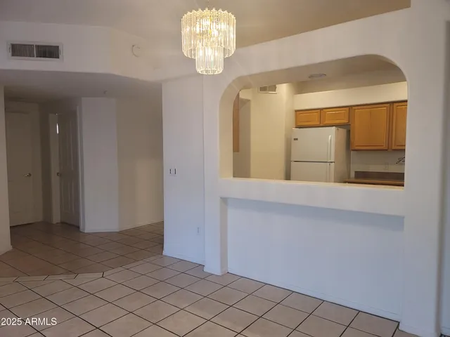 a view of an empty room and a chandelier fan