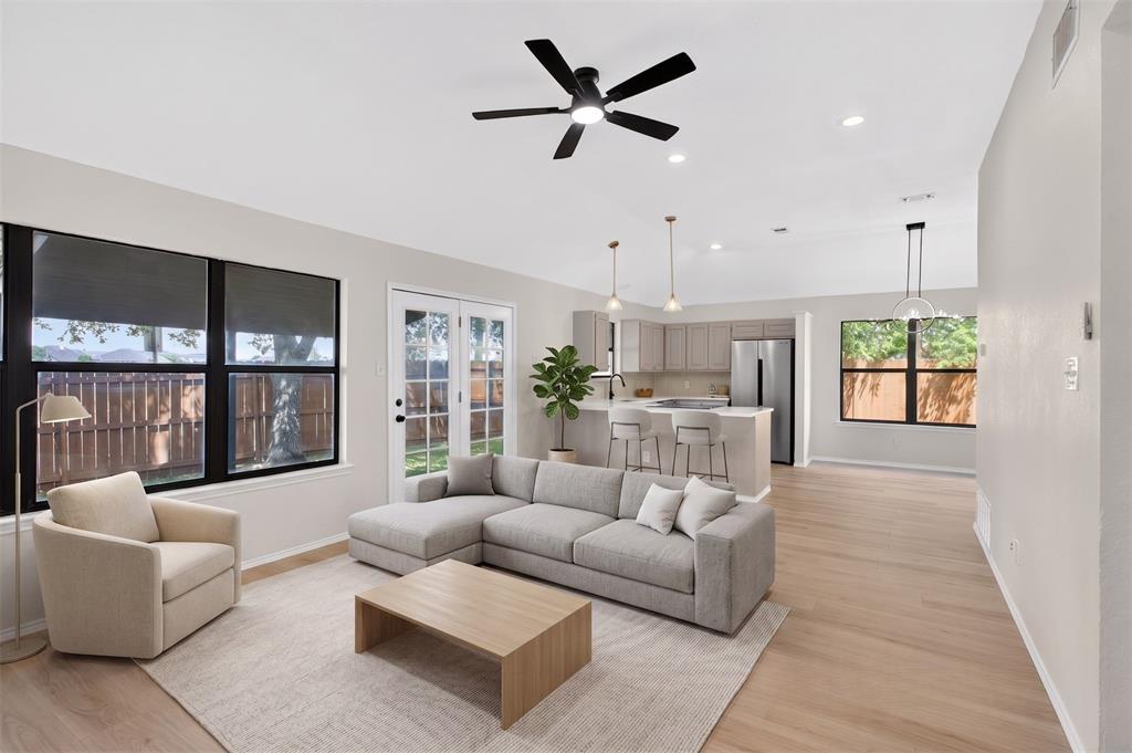 509 Brookside Court Burleson, TX 76028 - Photo 1 of 18 Open-concept living space featuring wood-finish flooring, a contemporary ceiling fan, recessed lighting, and a kitchen with pendant lighting and stainless steel appliances