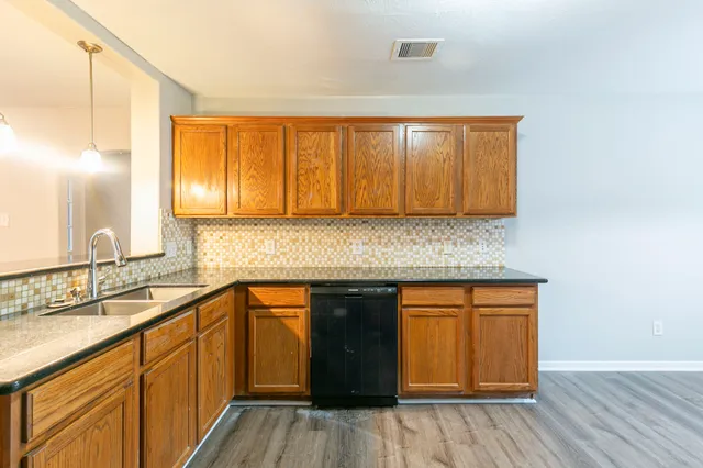 a kitchen with stainless steel appliances granite countertop wooden cabinets a sink and dishwasher