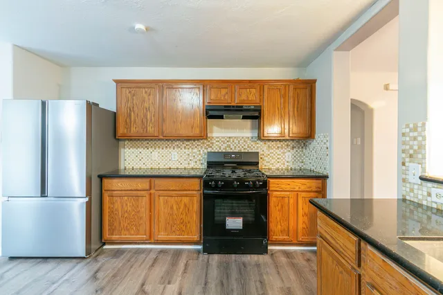 a kitchen with granite countertop wooden floors a stove and a refrigerator