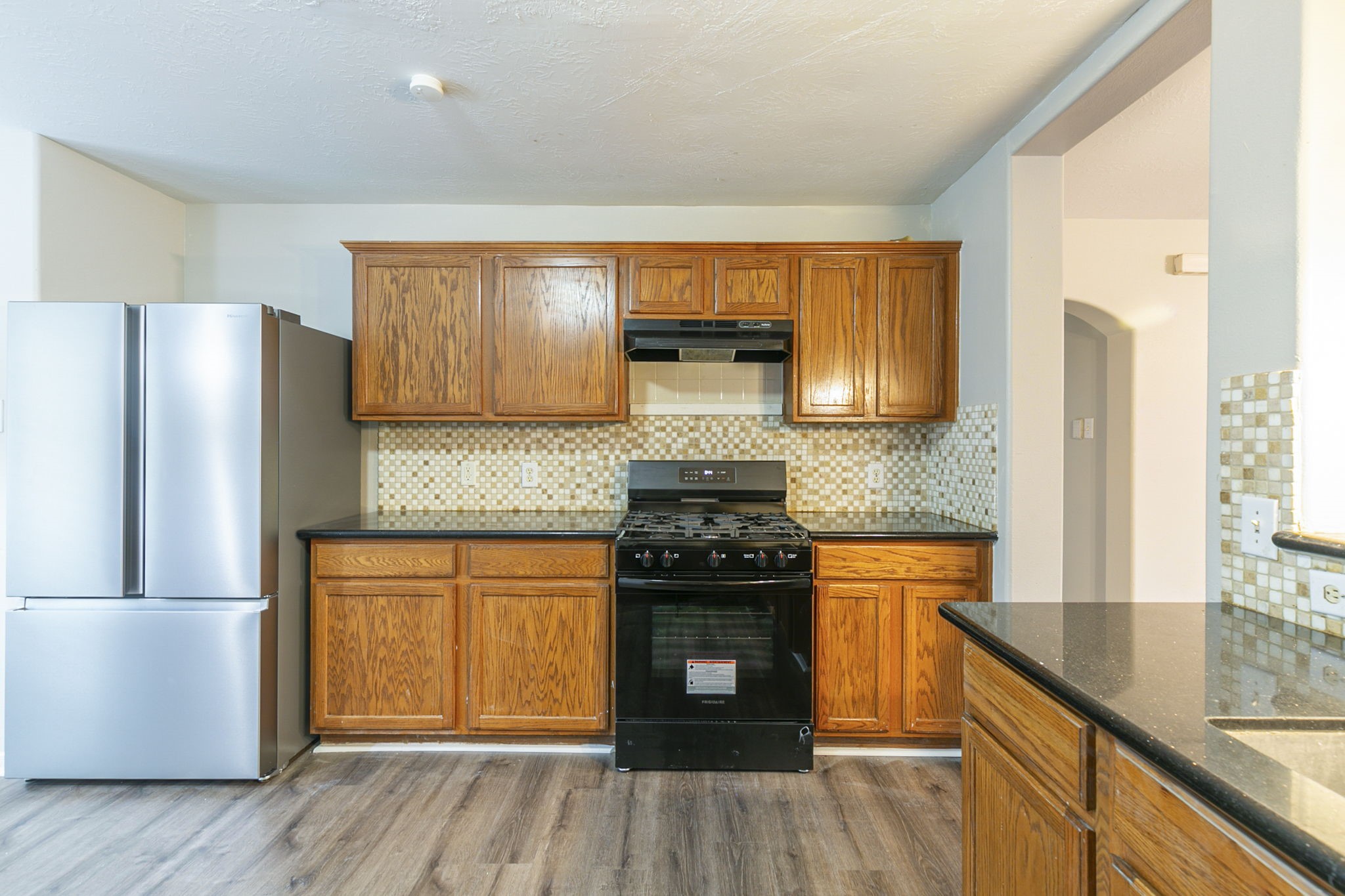 5601 Savannah Woods Lane Rosharon, TX 77583 - Photo 15 of 43 a kitchen with granite countertop wooden floors a stove and a refrigerator