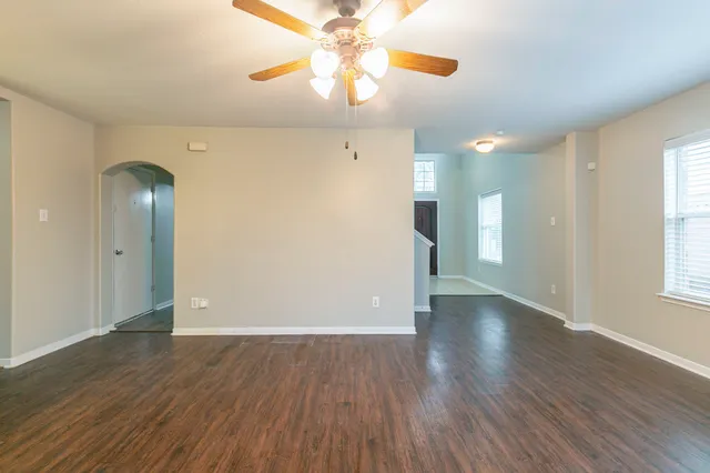 a view of an empty room with window and wooden floor