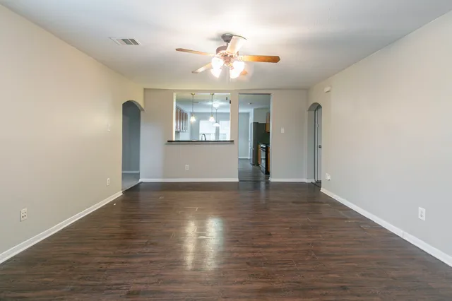 a view of an empty room with window and wooden floor