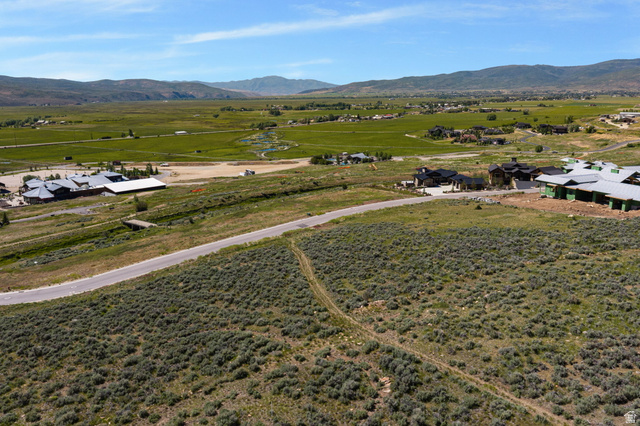 910 Wasatch Drive Kamas, UT 84036 - Photo 14 of 36 Expansive land parcel featuring natural shrubbery and a paved road, bordered by distant mountains