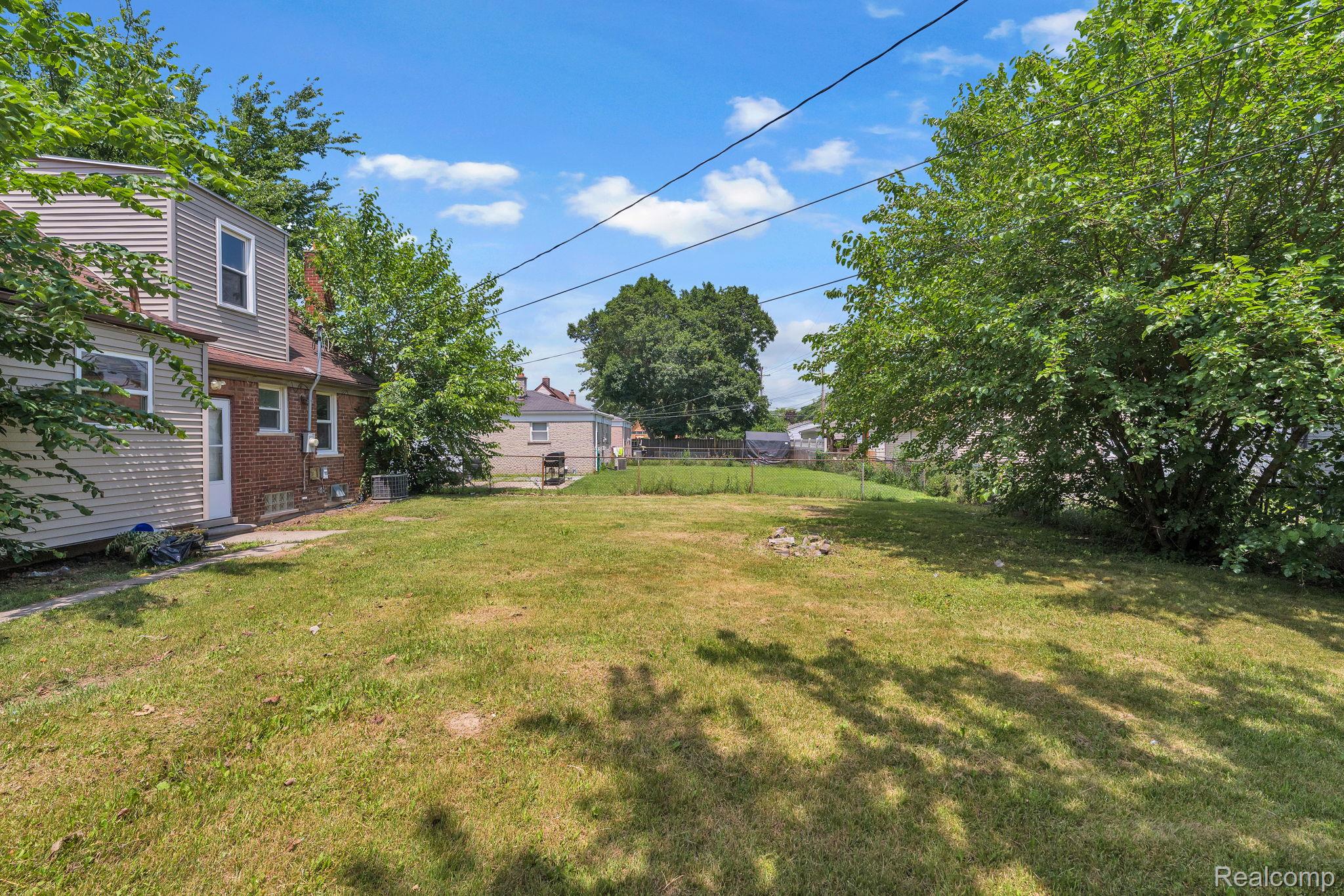 7641 Pelham Road Allen Park, MI 48101 - Photo 6 of 21 Expansive rear yard featuring a large grassy area, mature trees, and a two-story home with brick and siding facade