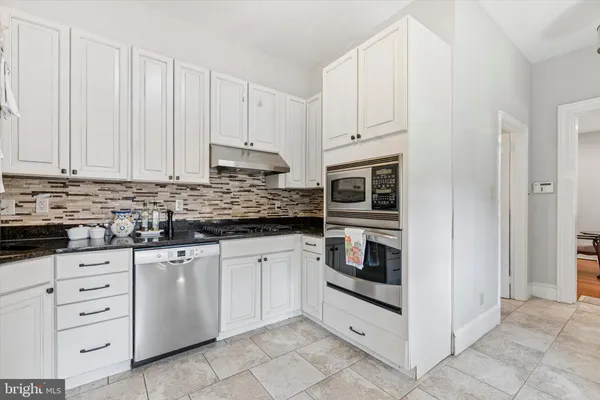 a kitchen with granite countertop white cabinets and stainless steel appliances