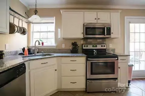 a kitchen with stainless steel appliances a stove a microwave a sink and white cabinets