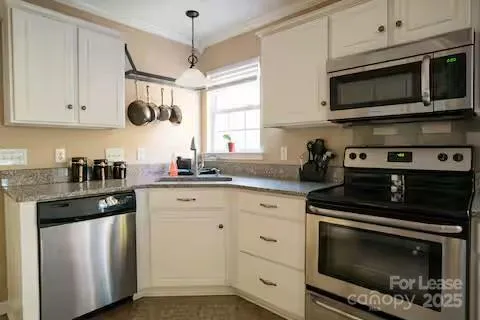 a kitchen with stainless steel appliances granite countertop white cabinets a sink a stove and a granite counter tops