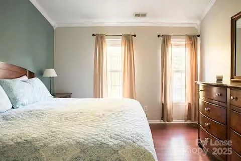 a large bedroom with a bed and wooden floor