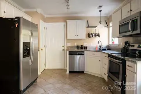 a kitchen with stainless steel appliances granite countertop a refrigerator a stove a sink and white cabinets with wooden floor