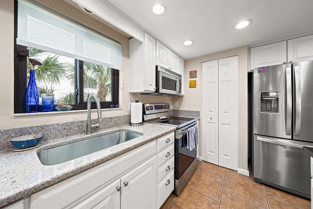 1206 Gulf Boulevard, Unit A6 Indian Rocks Beach, FL 33785 - Photo 11 of 61 a kitchen with stainless steel appliances granite countertop a refrigerator a sink a stove a microwave a counter space and cabinets