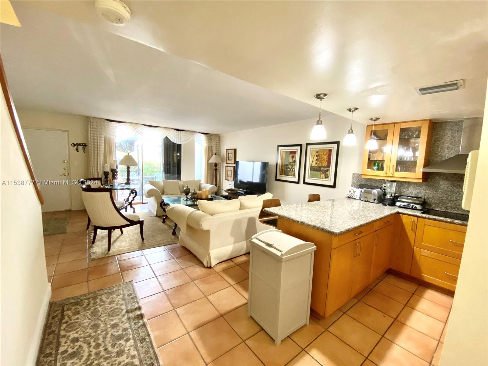 a large living room with stainless steel appliances kitchen island granite countertop a sink and cabinets